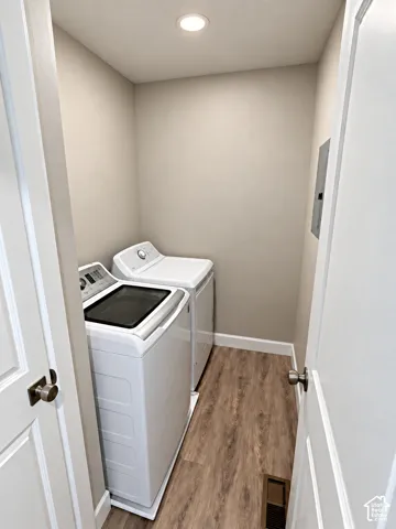 Dedicated laundry area featuring wood-finish flooring and recessed ceiling lighting