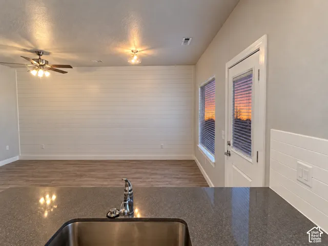 Wood-finish flooring, accent shiplap wall, ceiling fan, recessed lighting, and a stainless steel sink with a polished chrome faucet