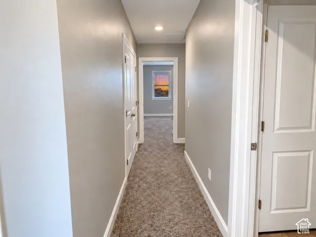 Carpeted hallway with light gray walls, white trim, and recessed lighting