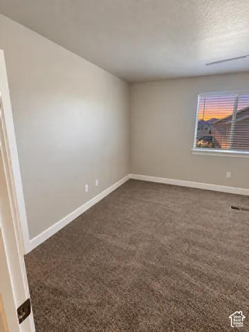 Neutral wall paint, plush carpeting, white trim, window with blinds, and ceiling-mounted light fixture