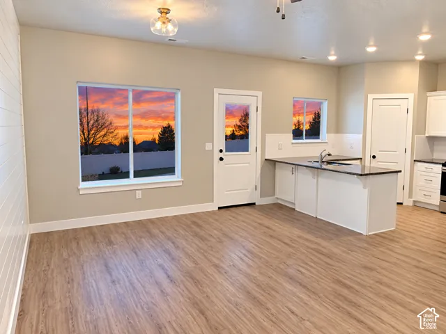 Wood-finish flooring throughout, white shaker cabinetry with dark countertops, white subway tile backsplash, and recessed lighting