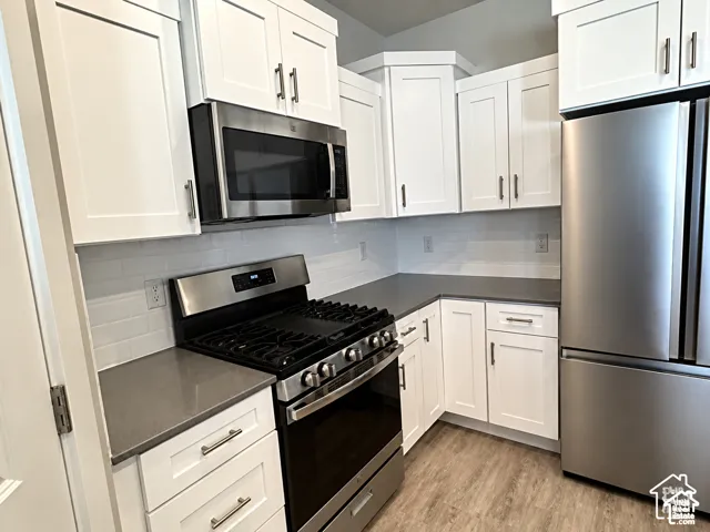 Kitchen featuring white shaker cabinetry, stainless steel appliances, grey countertops, and subway tile backsplash