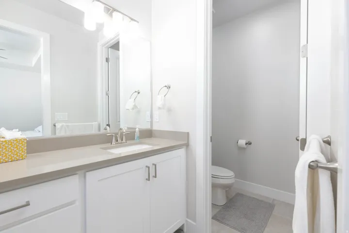 Bathroom vanity featuring a single integrated sink, light-toned countertop, and white cabinetry with brushed nickel hardware