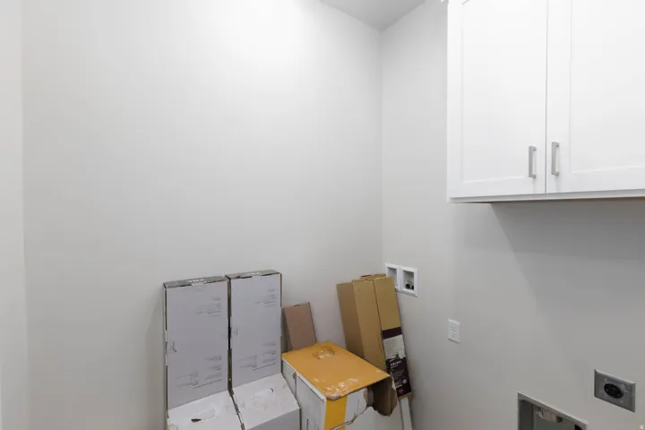 Laundry area featuring white shaker-style cabinetry with brushed nickel hardware
