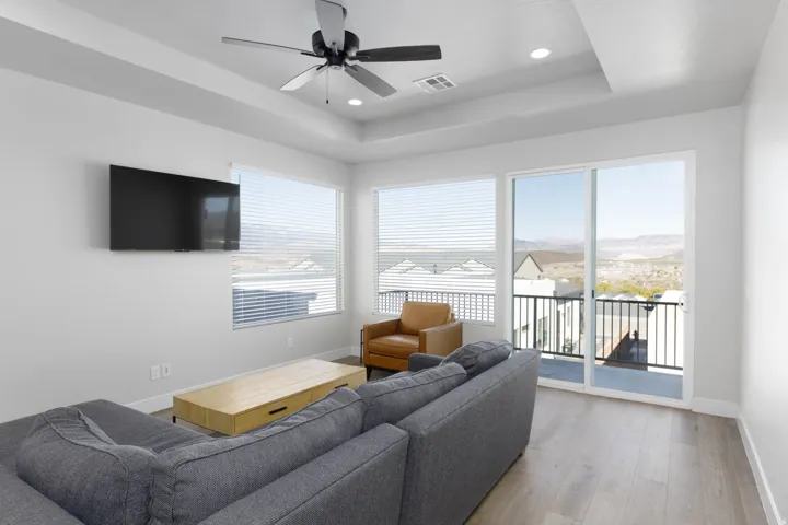 Spacious living area featuring light wood-finish flooring and a contemporary ceiling fan
