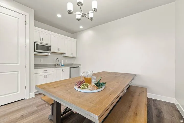 Compact kitchen space featuring white cabinetry, a built-in microwave, stainless steel sink, and a mini-refrigerator