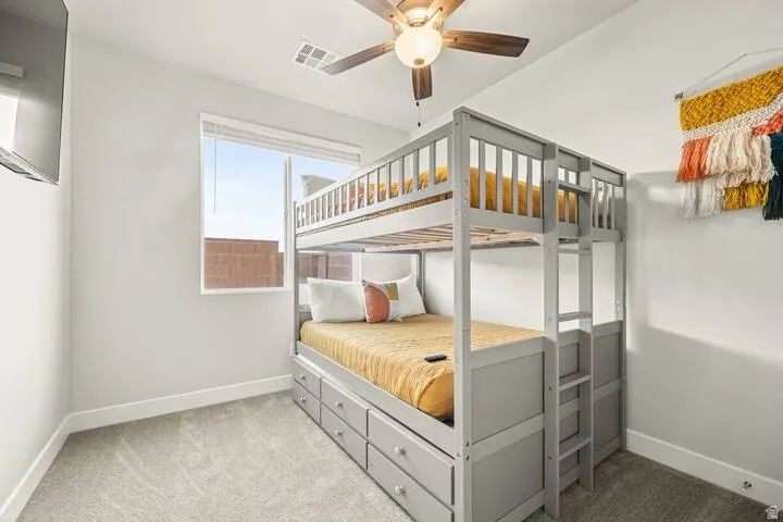 Carpeted room with a ceiling fan, a window with blinds, and white baseboards
