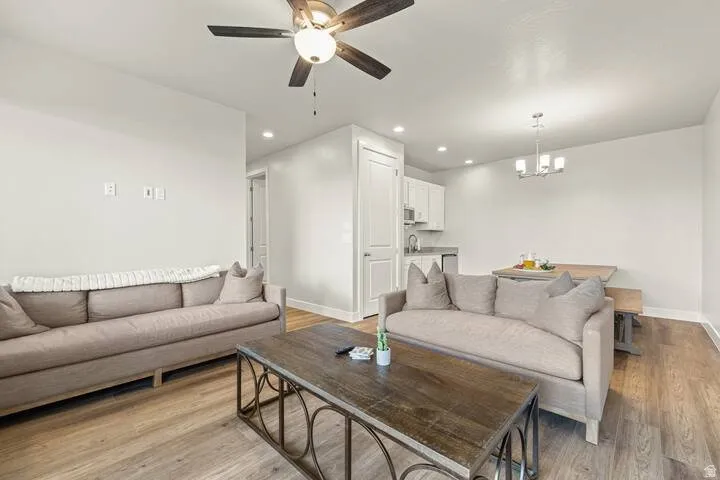 Open-concept living space with wood-finish flooring, white walls, and a ceiling fan