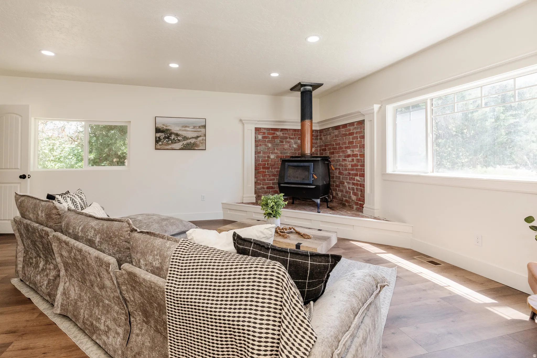Living space featuring a corner wood-burning stove with a brick surround and white mantel