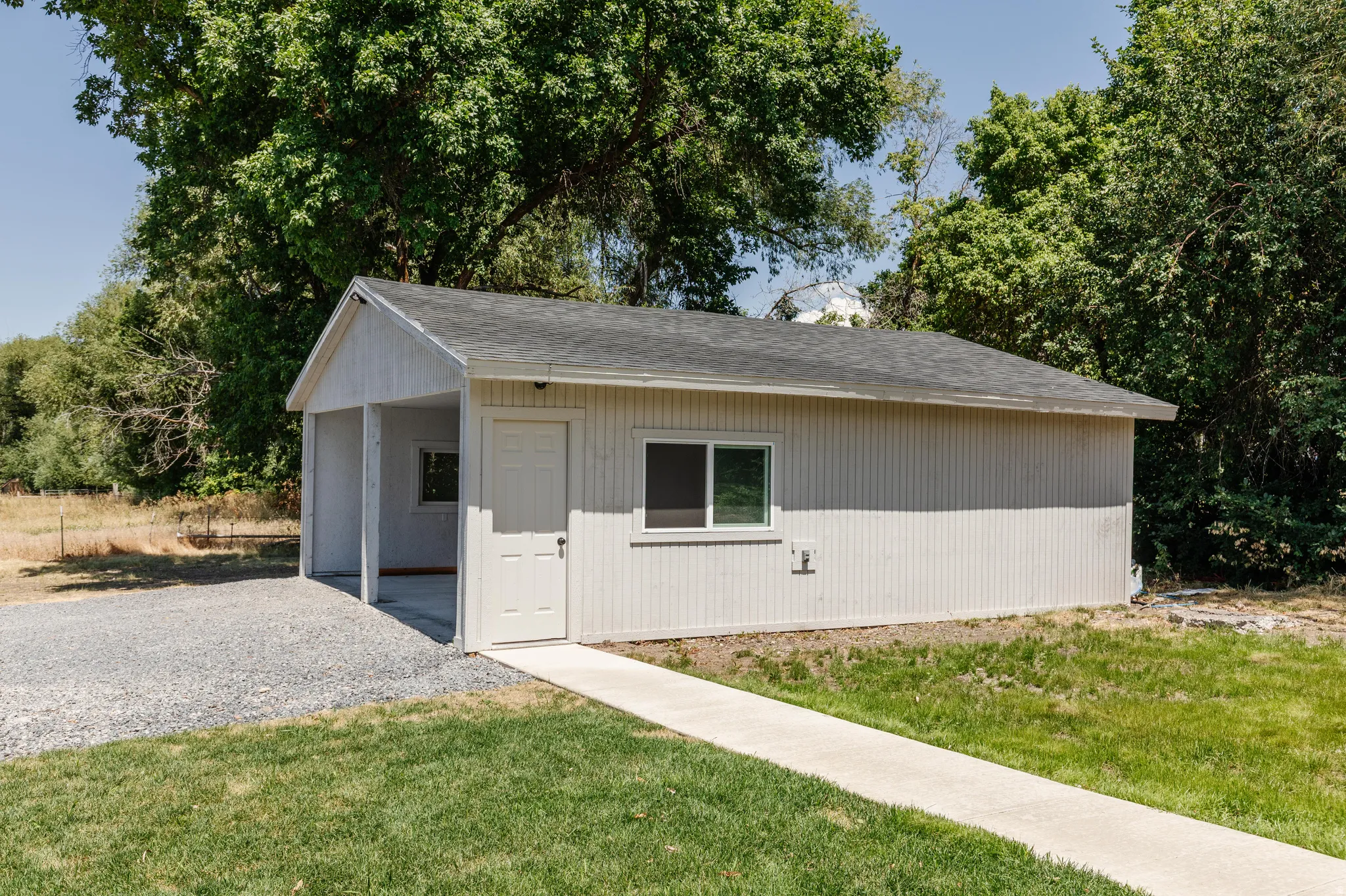 Detached auxiliary structure featuring vertical siding, an asphalt shingle roof, and a covered carport area