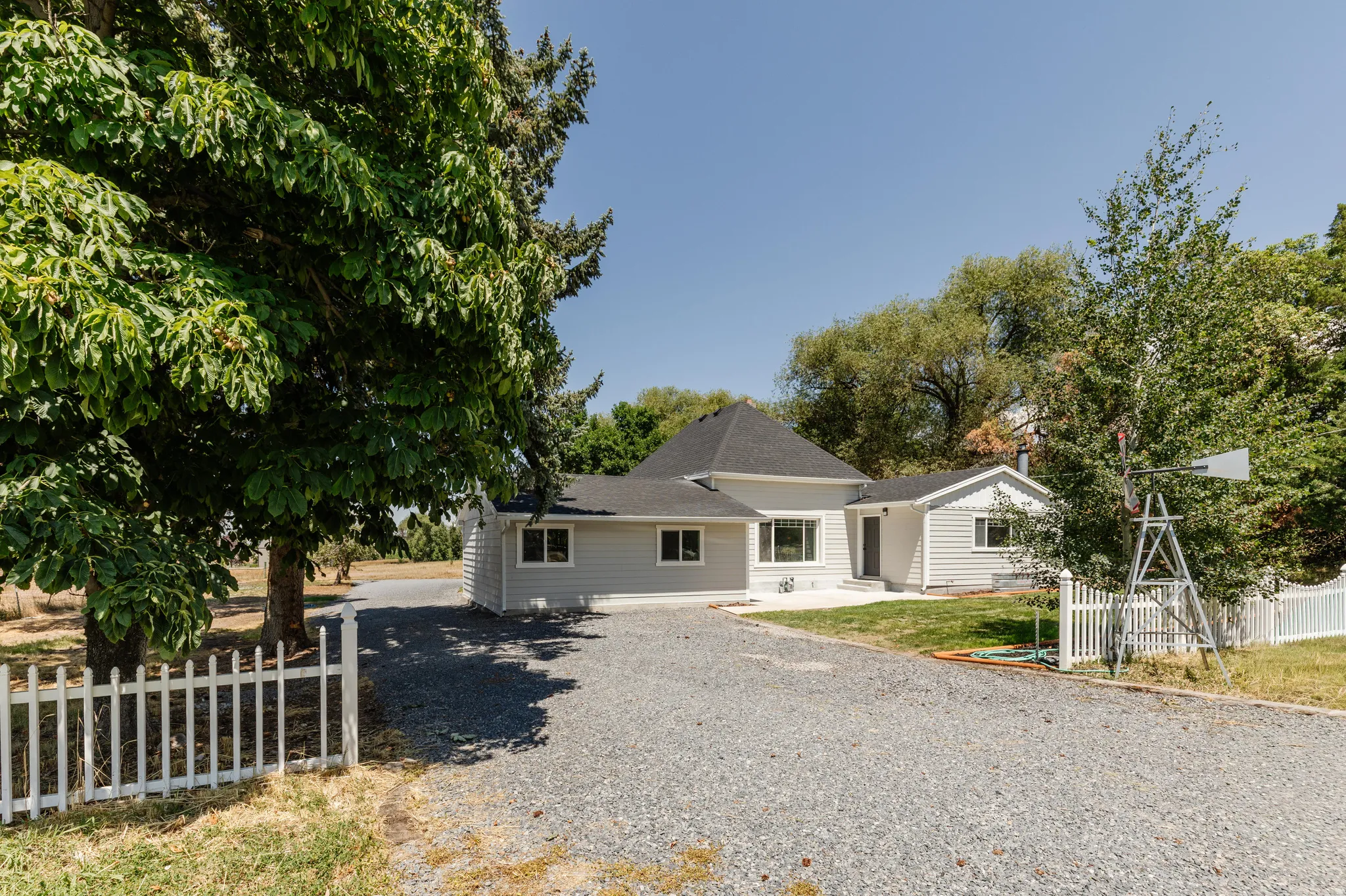 Ranch-style residence featuring light gray siding and a dark shingled roof
