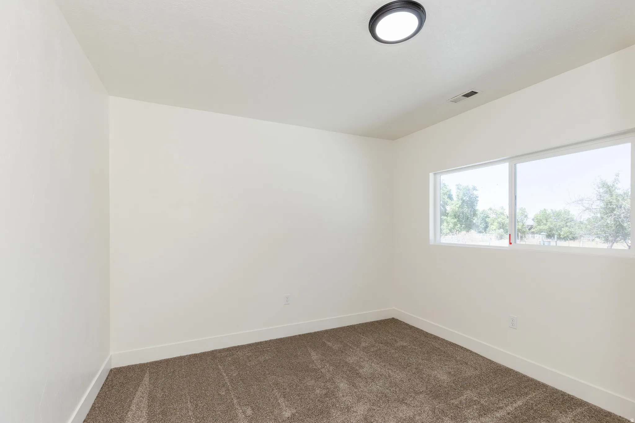 Room with neutral carpeting and a window offering natural light