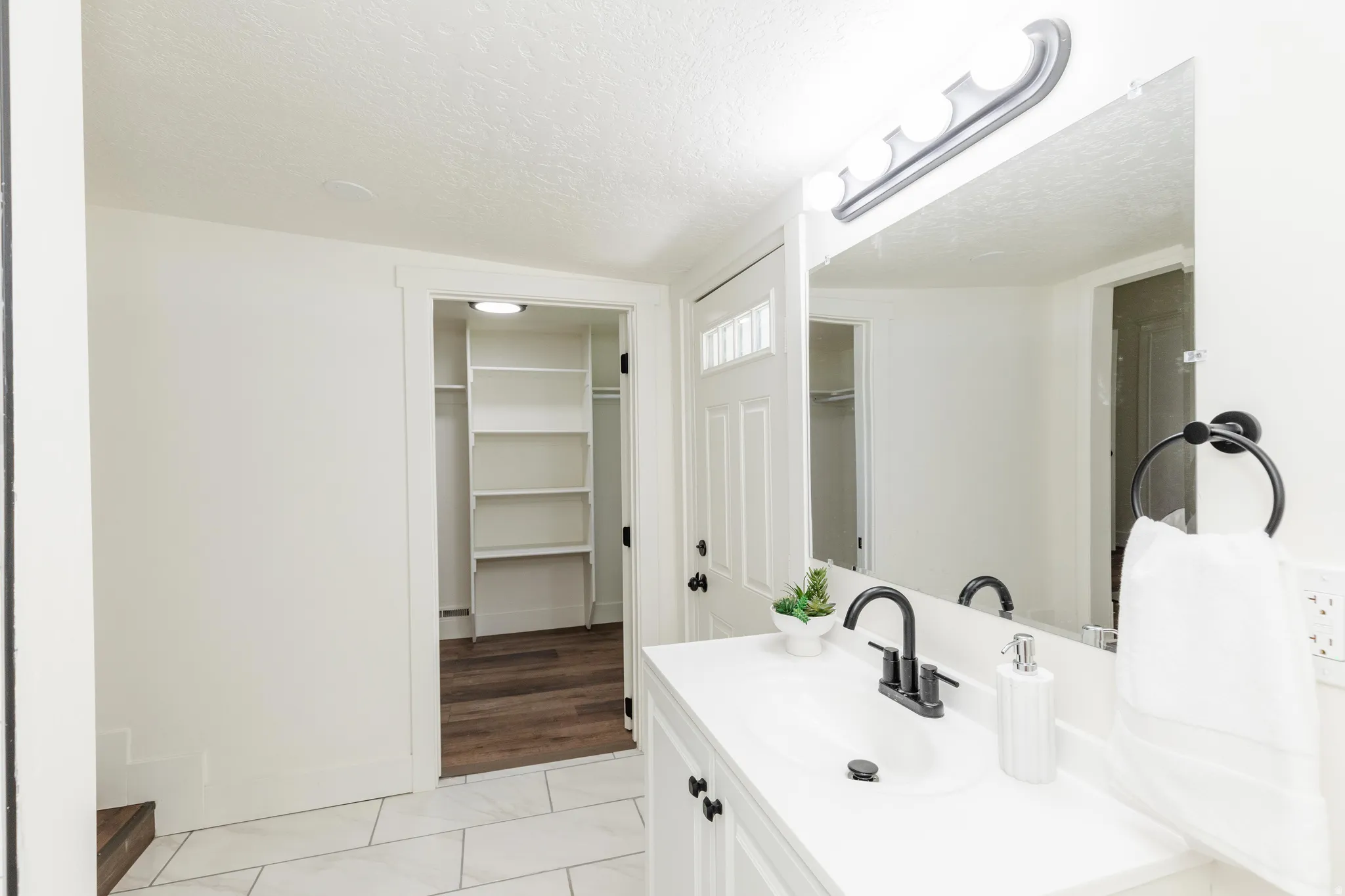 Bathroom vanity with white countertop, undermount sink, and matte black faucet