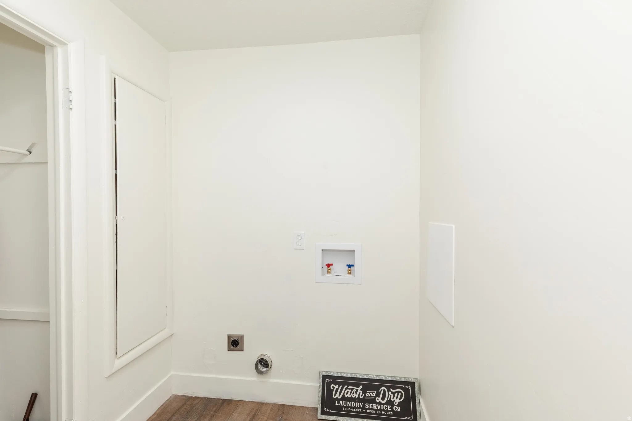 Dedicated laundry area featuring hookups for washer and dryer, wood-finish flooring, and crisp white walls