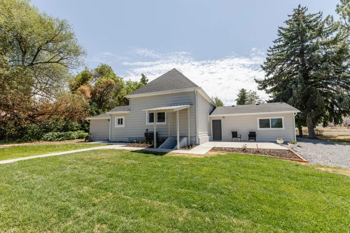 Expansive grass lawn with concrete walkways leading to a covered entryway and patio