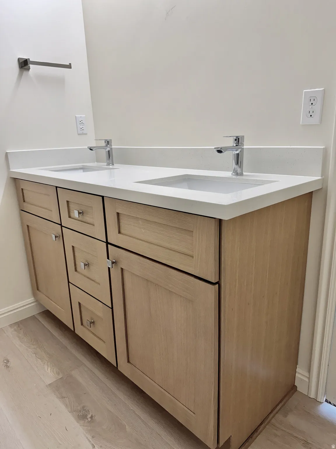 Double vanity with light wood-finish cabinetry, white countertop, and integrated sinks