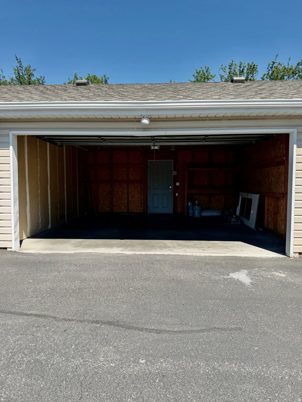 Attached garage featuring vinyl siding, an asphalt shingle roof, and a concrete floor