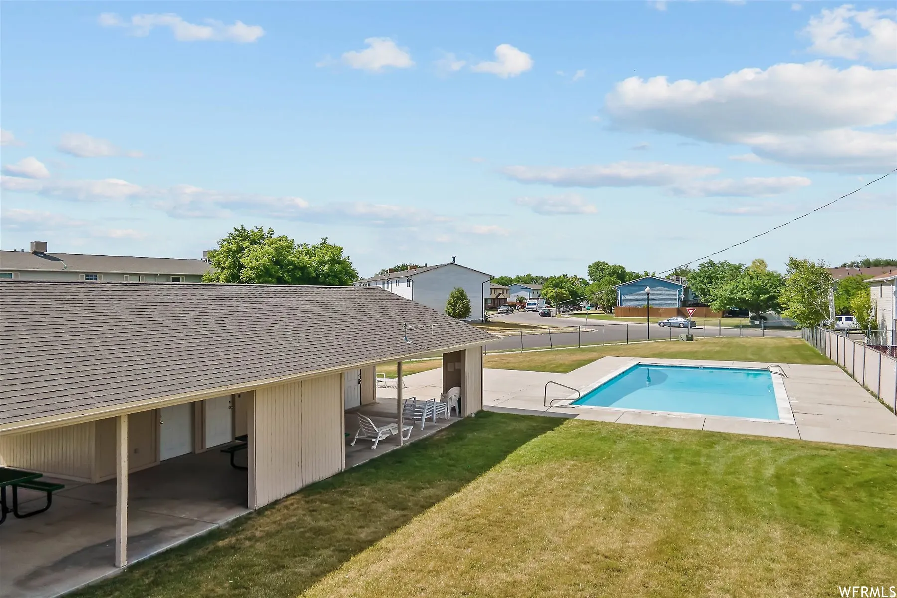 Outdoor swimming pool with concrete surround, surrounded by a grassy lawn