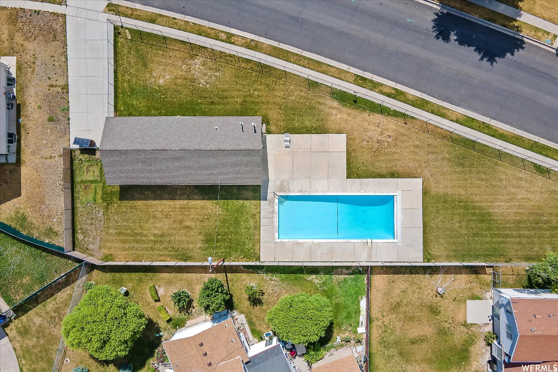 Rectangular swimming pool with concrete surround and expansive yard space