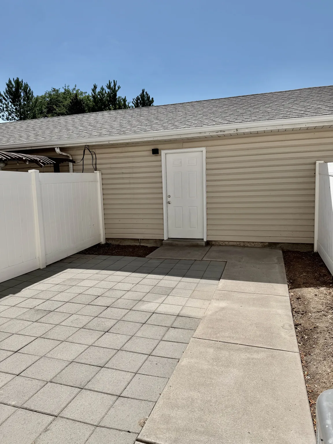 Enclosed patio area featuring square paver stones and a concrete pathway