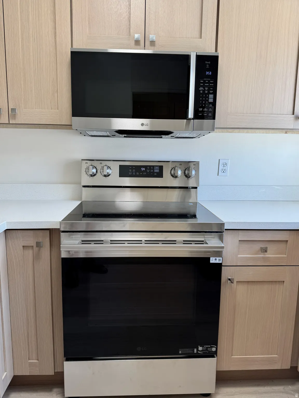 Stainless steel range and microwave oven set against light wood-finish cabinetry
