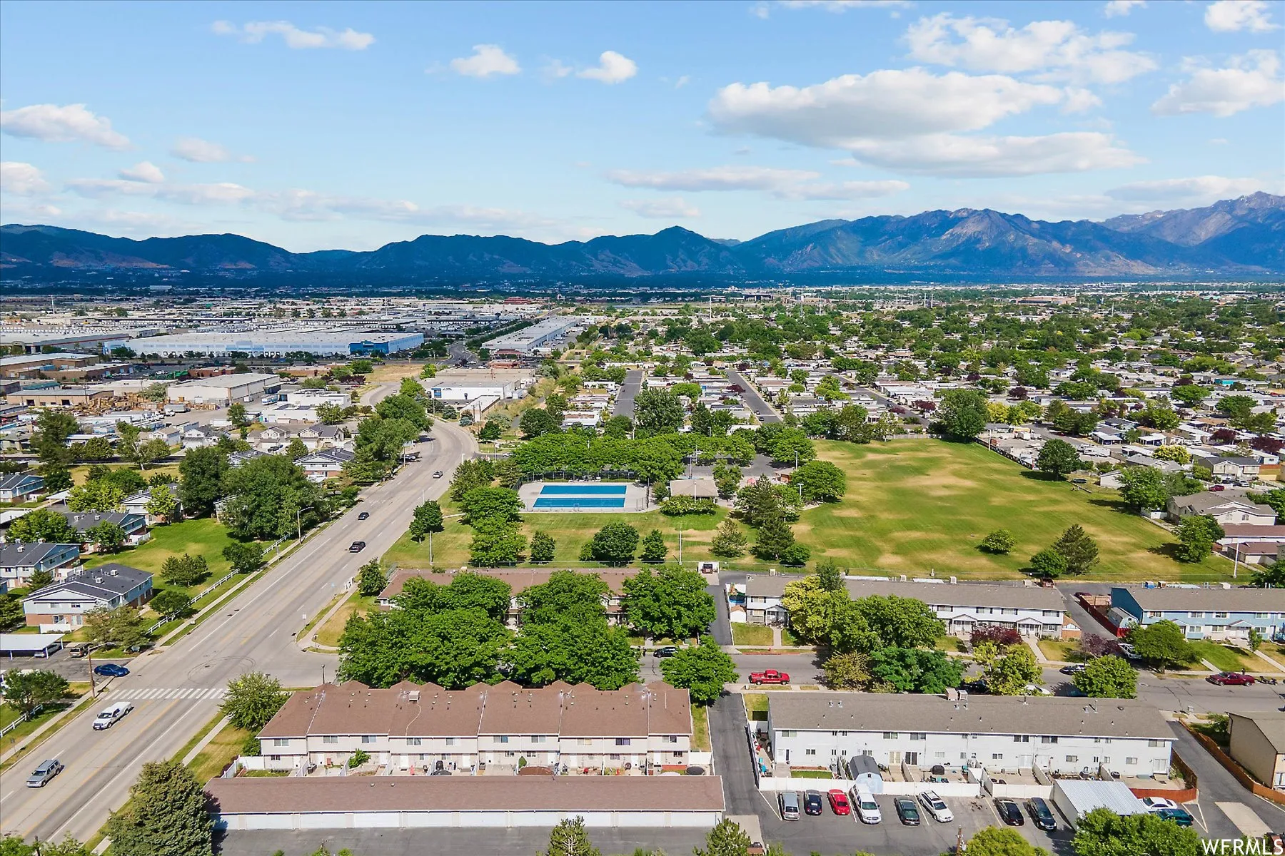 Aerial overview showcasing residential properties, a large community green space, and a swimming pool