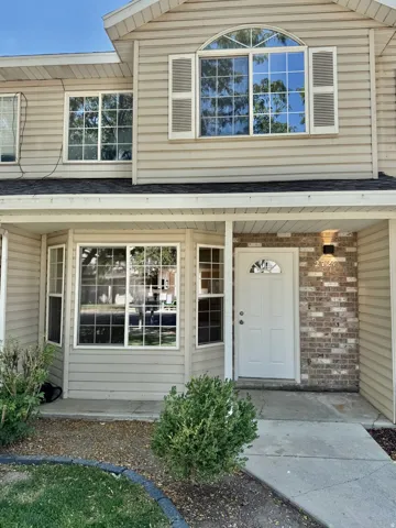 Two-story exterior featuring beige horizontal siding and brick accents