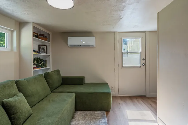Room featuring wood-finish flooring, built-in shelving, a mini-split climate control system, and a door with an upper window