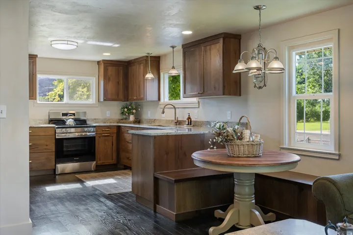 Kitchen featuring dark wood-finish flooring, stainless steel range, light-toned countertops, wood cabinetry, and a built-in bench seating arrangement
