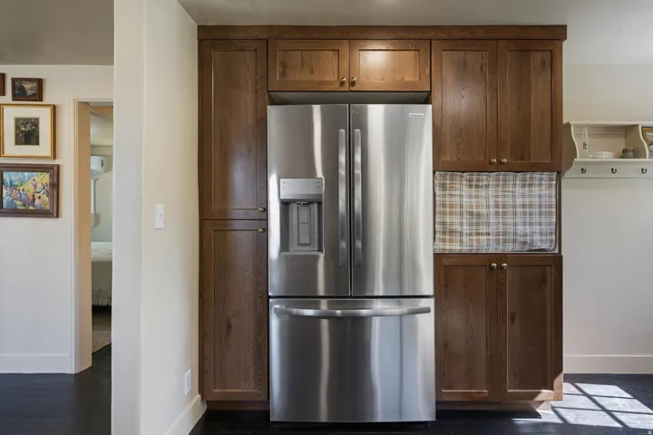 Stainless steel French-door refrigerator integrated with wood-finish cabinetry