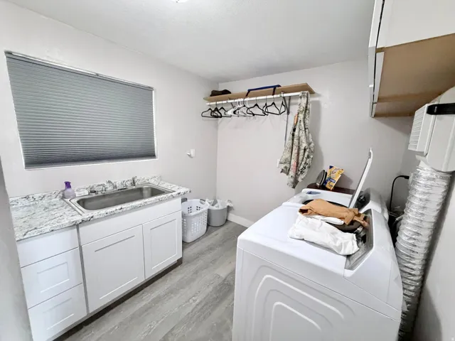 Laundry room with cabinet space, light wood finished floors, and washing machine and clothes dryer