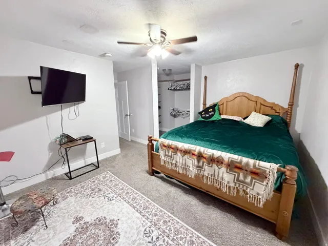 Bedroom with light colored carpet, a ceiling fan, and a textured ceiling