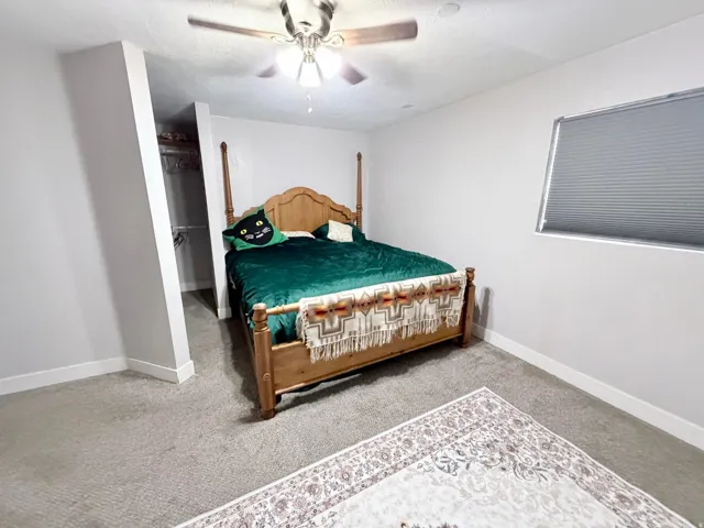 Bedroom featuring light carpet, a ceiling fan, and a spacious closet