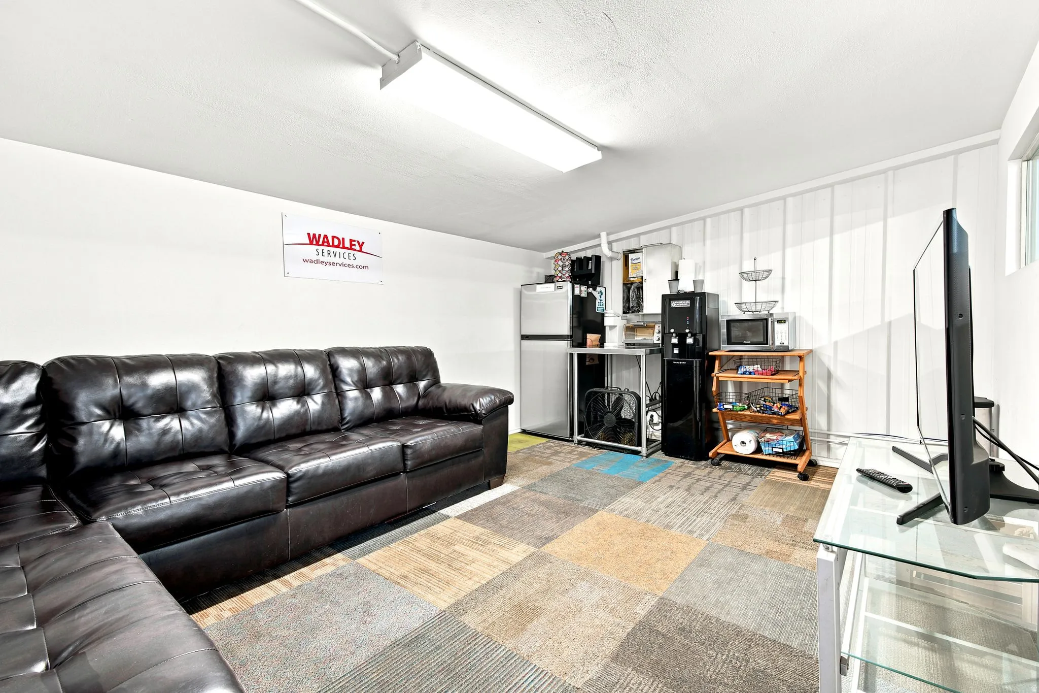 Versatile space featuring a drop ceiling with track lighting, white painted walls, and carpet tile flooring