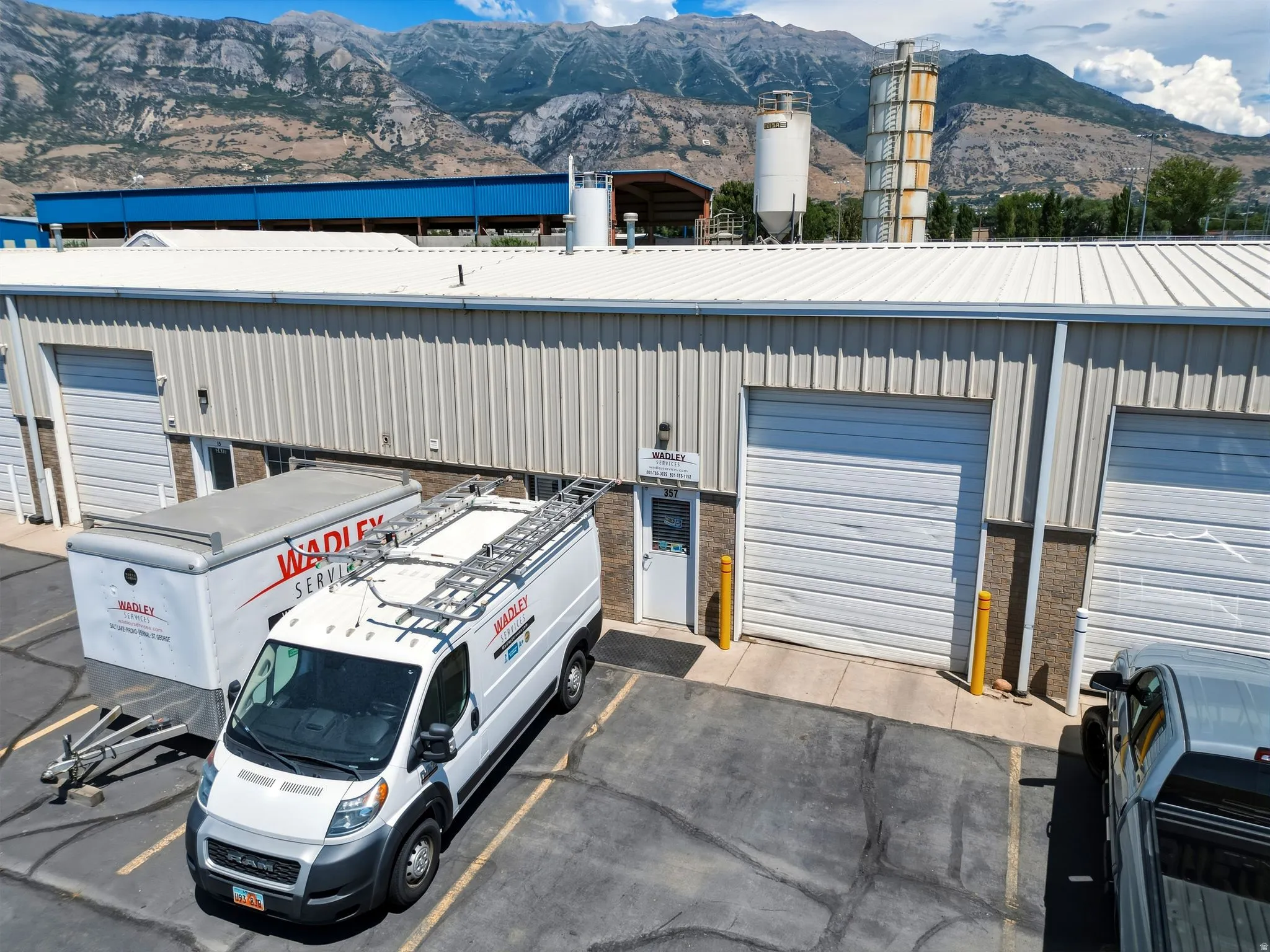 Commercial building featuring corrugated metal siding, multiple roll-up garage doors, and a prominent mountain backdrop