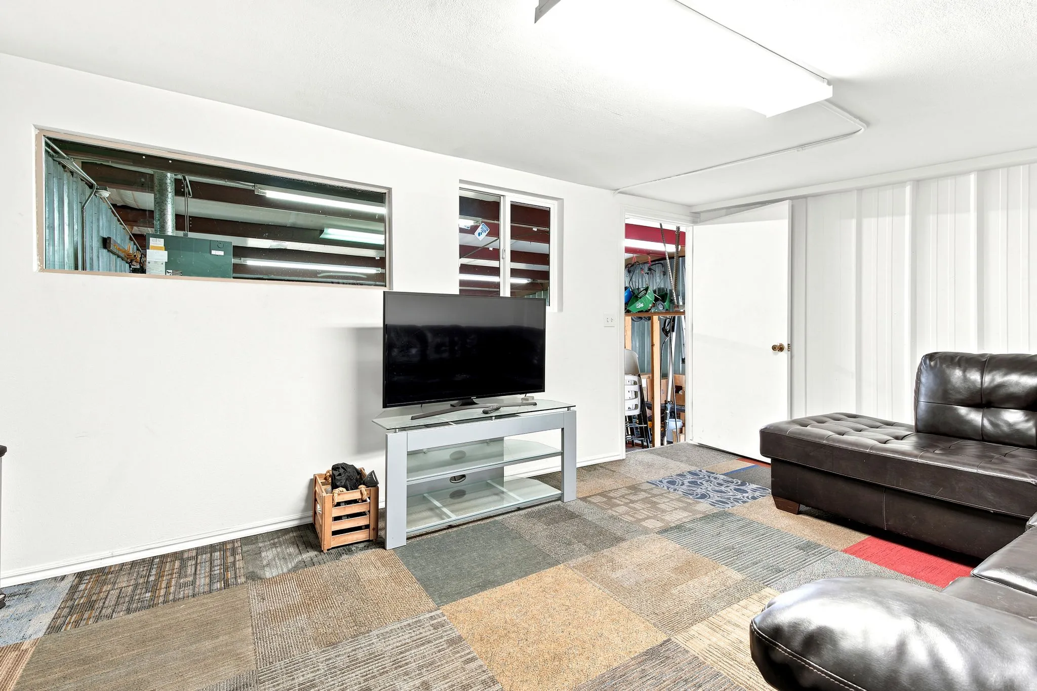Carpet tile flooring with diverse patterns, white painted walls, two rectangular windows, and a flush-mount ceiling light