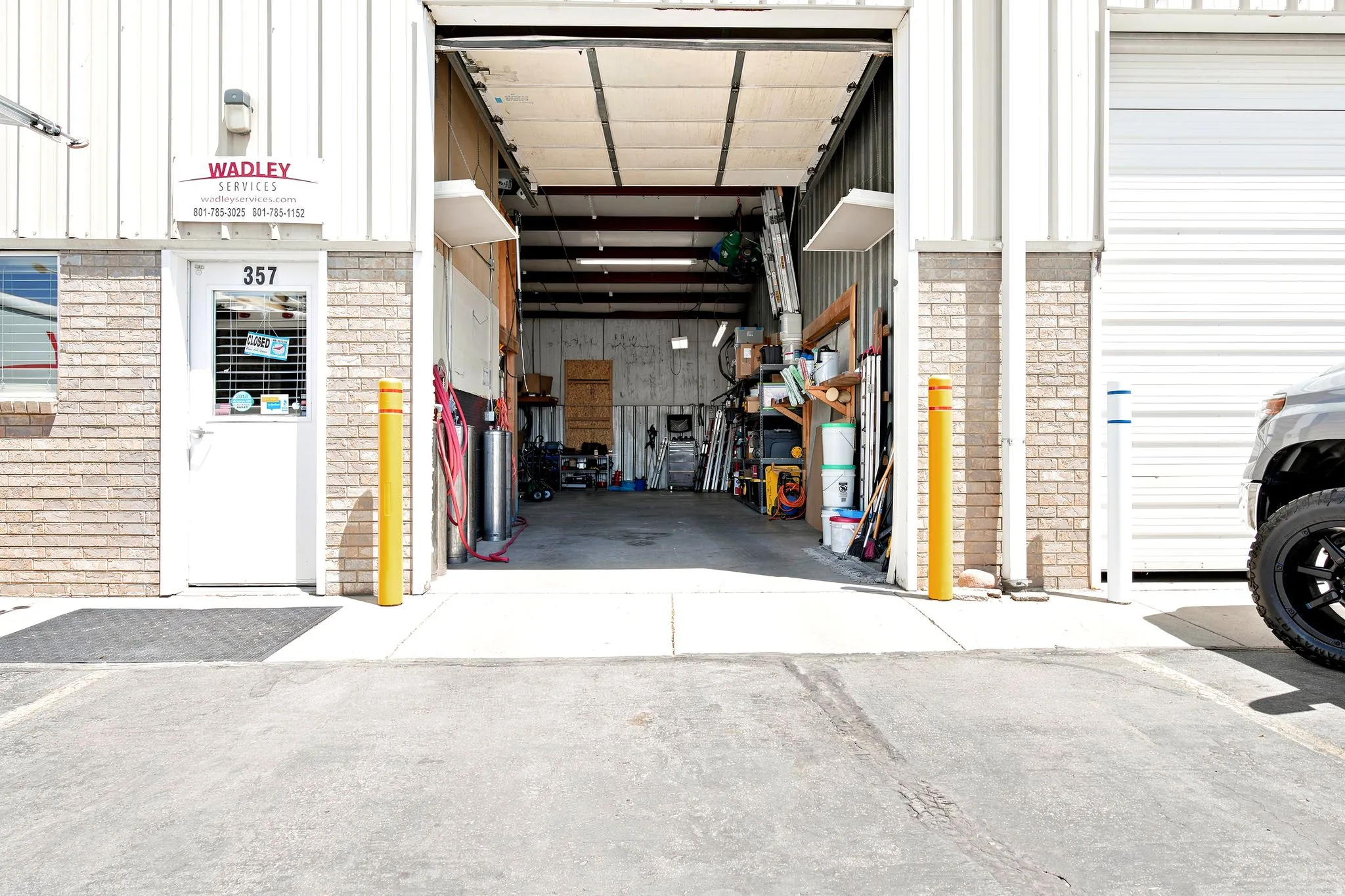 Commercial building featuring a large open bay with industrial-style overhead door, a separate pedestrian entrance, and brick accents