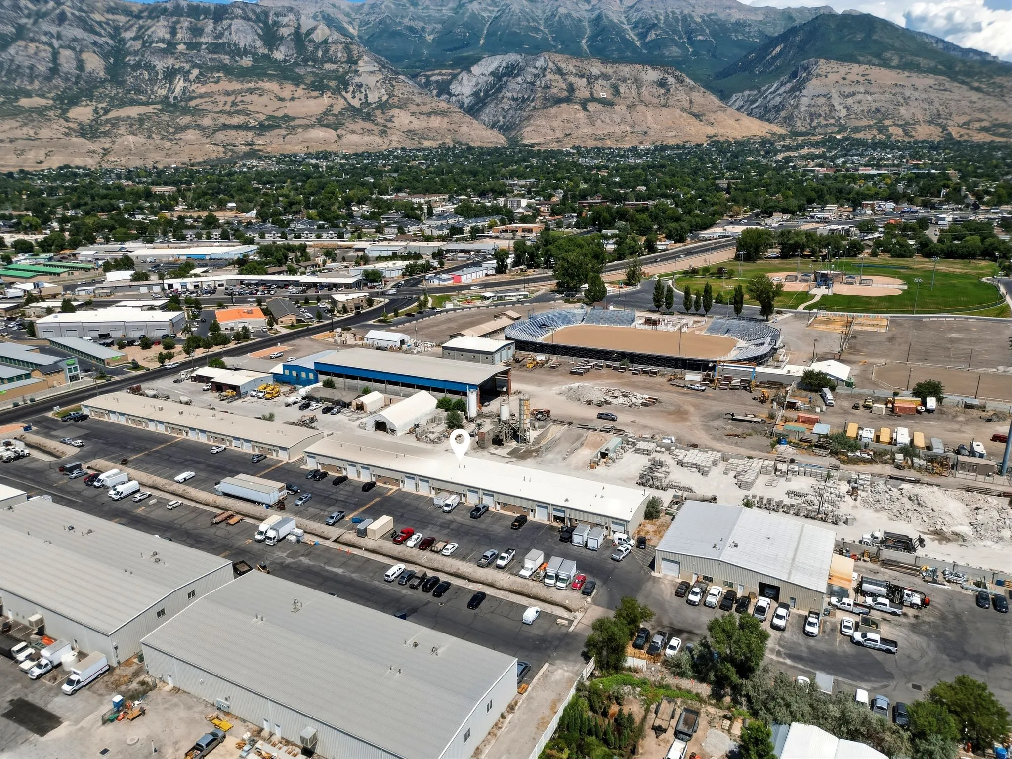 Expansive industrial complex featuring multiple large buildings with light-colored roofs, ample paved parking areas, and adjacent open storage space