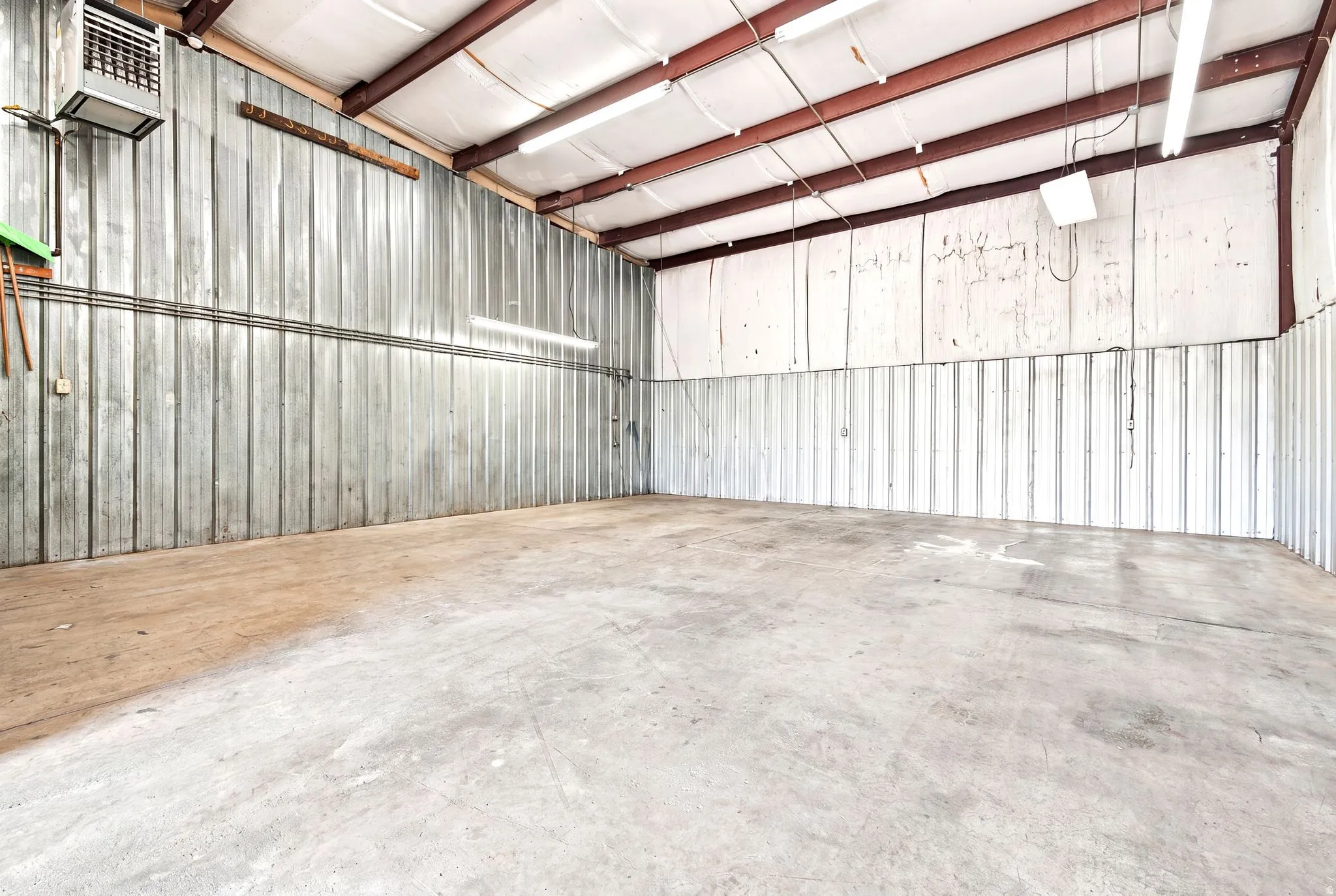 Spacious commercial interior featuring concrete flooring and corrugated metal wall panels