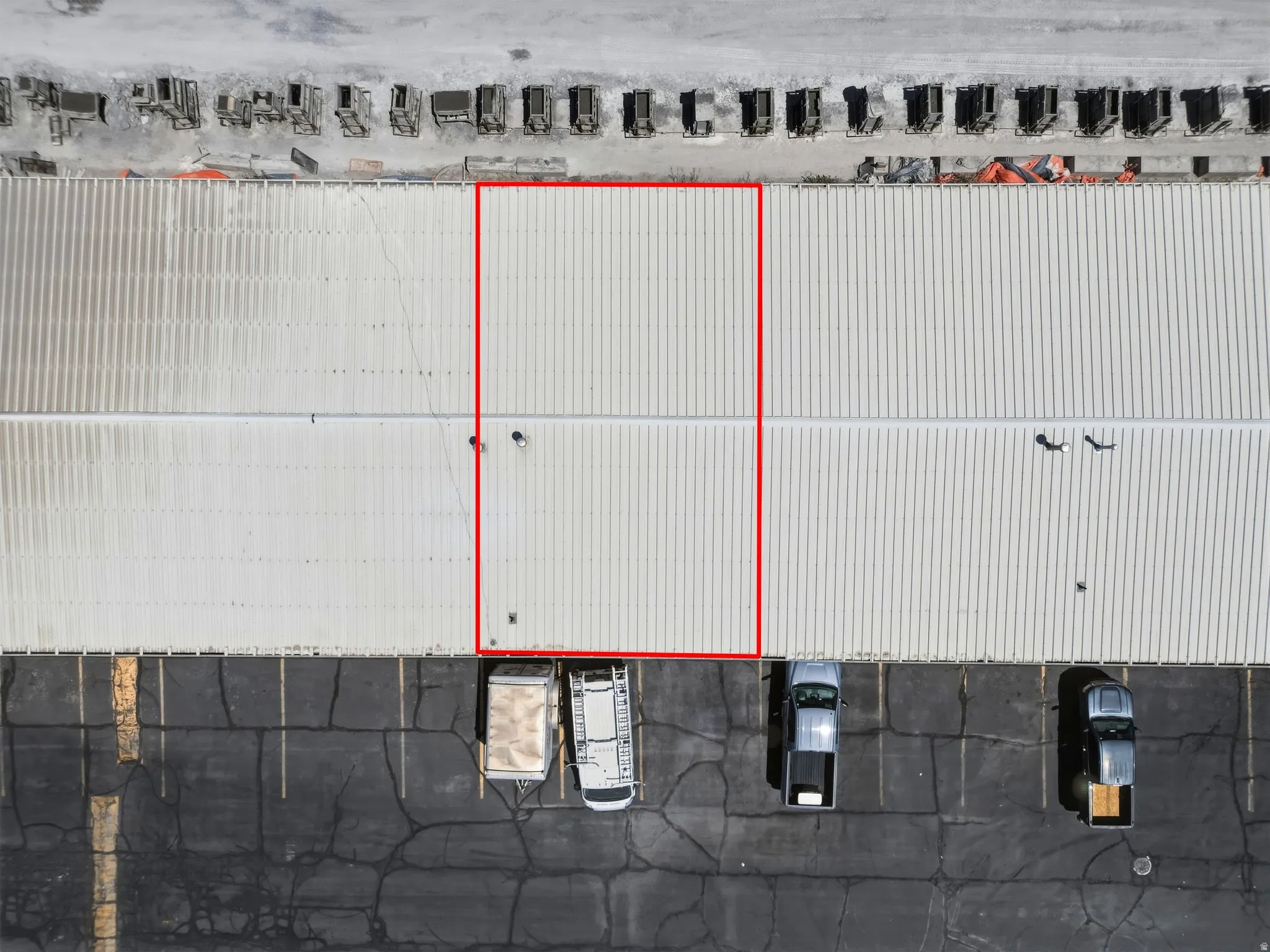 Industrial building with a large corrugated metal roof and expansive paved parking area