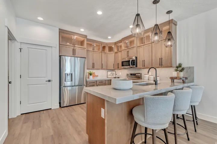 Modern kitchen featuring wood-finish flooring, light wood cabinetry, recessed lighting, and a kitchen island with a light-toned countertop