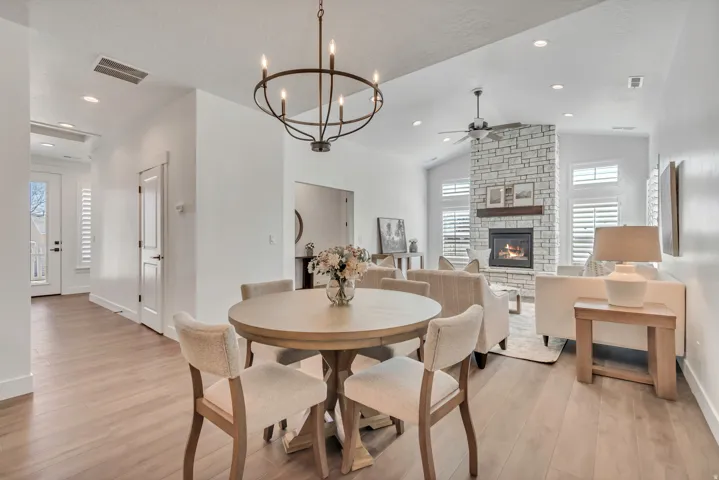 Open-concept living space with wood-finish flooring, a stone fireplace, vaulted ceilings, a ceiling fan, and recessed lighting