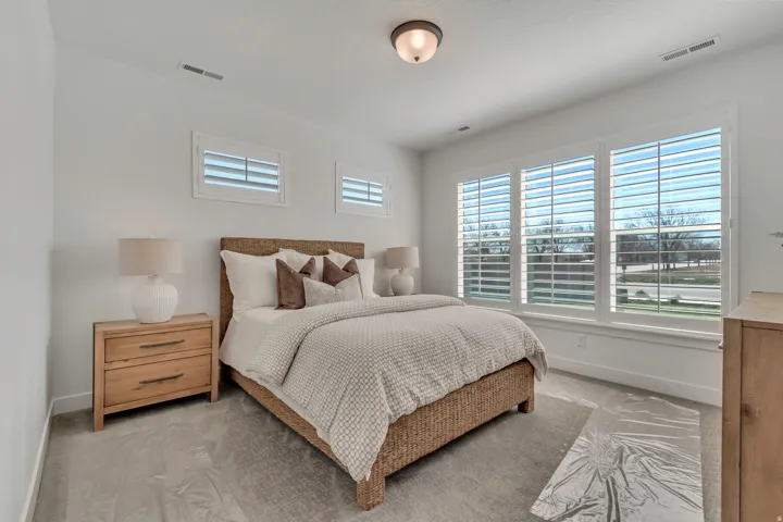 Bright room featuring three large windows with white louvered shutters and two smaller transom windows