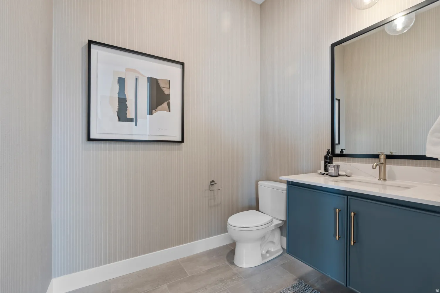 Bathroom featuring a floating vanity with a white countertop and integrated sink, a large black-framed mirror, and a contemporary wall-mounted light fixture