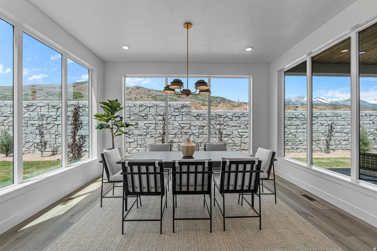 Dining area featuring expansive windows, wood-finish flooring, and a contemporary chandelier
