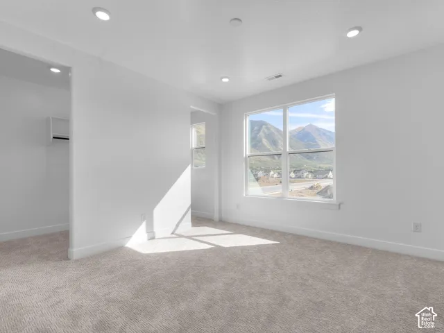 Neutral-toned wall-to-wall carpeting, recessed ceiling lighting, large window with mountain scenery, and built-in closet shelving