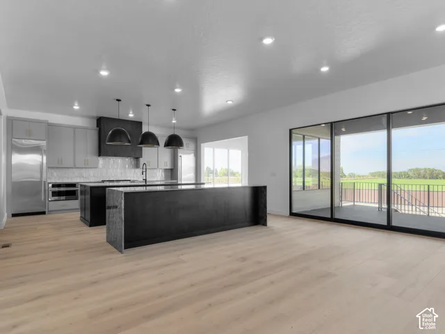 Kitchen featuring wood-finish flooring, dual islands with stone-top counters, modern matte-finish cabinetry, recessed lighting, and large glass sliding doors