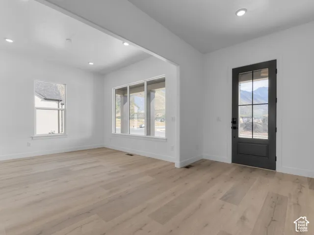 Light-filled room featuring wood-finish flooring, recessed lighting, multi-pane windows, and a matte black six-panel glass door with mountain scenery