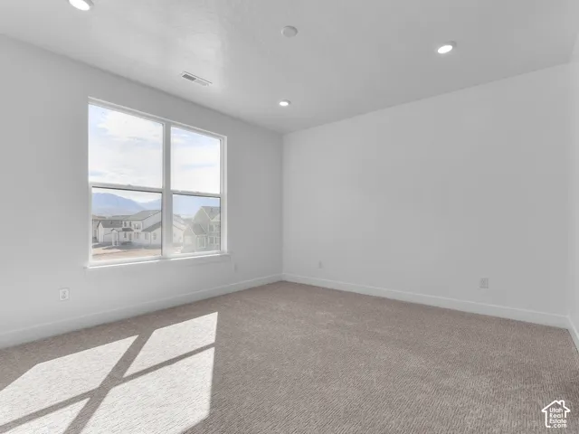 Neutral-toned carpeted interior featuring recessed lighting, smooth wall finishes, and a double-pane window