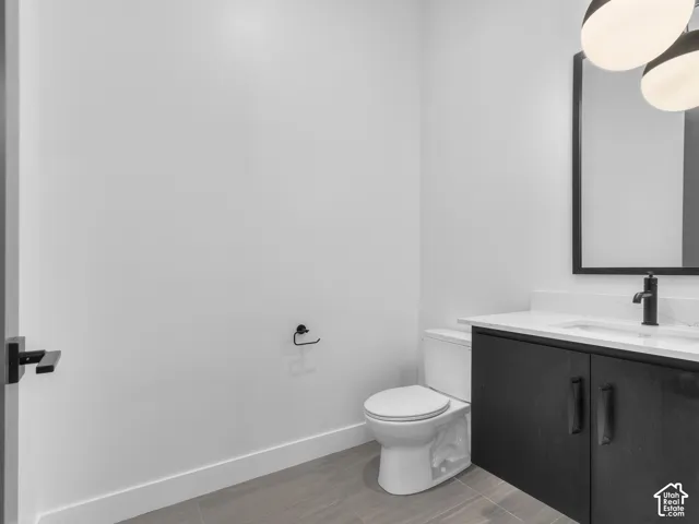 Modern vanity with black cabinetry, solid surface countertop, matte black faucet, framed mirror, and wood-finish tile flooring